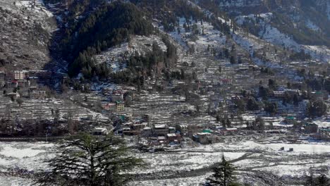 Aerial-Truck-Down-shot-of-Vashist-village-covered-with-snow-after-heavy-snowfall-in-the-winters,-shot-with-a-drone-in-4k