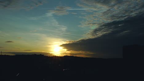 Ein-Strahlend-Blauer-Himmel-Mit-Einem-Orangefarbenen-Sonnenuntergang-Ist-Von-Dunklen-Wolken-Bedeckt,-Wolken-Bewegen-Sich-Und-Bilden-Neue-Schichten-Am-Himmel