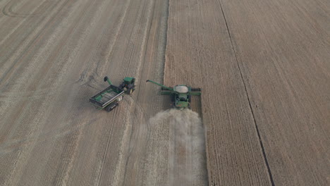 Drone-view-of-grain-cart-tractor-pulling-into-position-for-dumping-full-combine-harvester
