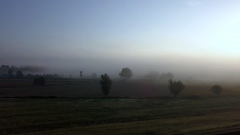 Tuscan-countryside-fields-in-Italy-as-sun-rises-on-a-cold-foggy-morning,-Aerial-dolly-in-reveal-shot