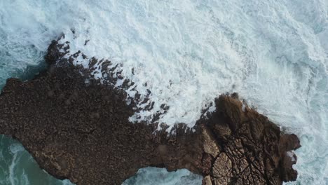 Large-Ocean-rock-battered-by-waves-in-Praia-Do-Tonel,-near-Cape-Sagres-Portugal,-Aerial-rising-shot