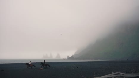 Pferde,-Die-In-Zeitlupe-über-Den-Schwarzen-Sandstrand-Laufen,-An-Einem-Nebligen-Tag-In-Vik,-Island