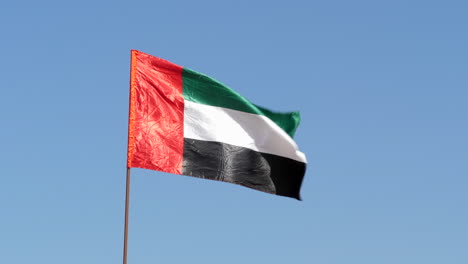 Bandera-De-Los-Emiratos-árabes-Unidos-Ondeando-En-El-Viento-Frente-Al-Cielo-Azul