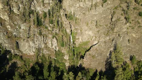 Aerial-dolly-out-of-Corbata-Blanca-thin-waterfall-falling-between-mountains-with-pine-trees,-Patagonia-Argentina