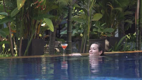 Totale-Einer-Jungen-Frau,-Die-Sich-Am-Pool-Entspannt-Und-In-Einem-Tropischen-Hotel-Einen-Cocktail-Genießt