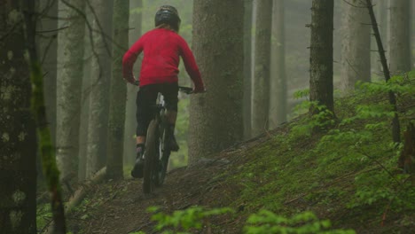 Mountain-biker-pedals-on-a-foggy-trail-inside-a-luxuriant-forest
