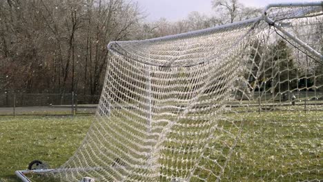 Zeitlupe:-Ein-Fußball-Knallt-Ein-Eisiges-Netz-Eines-Fußballtors,-Das-Zerschmettertes-Eis-In-Die-Luft-Explodiert