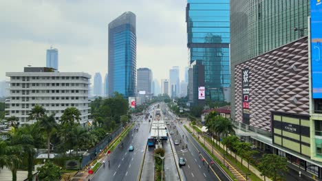 Main-street-of-Jakarta-downtown,-skyscrapers-with-led-screen-adverts-aerial-view