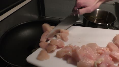 Sliced-pieces-of-chicken-being-put-into-pan-for-frying