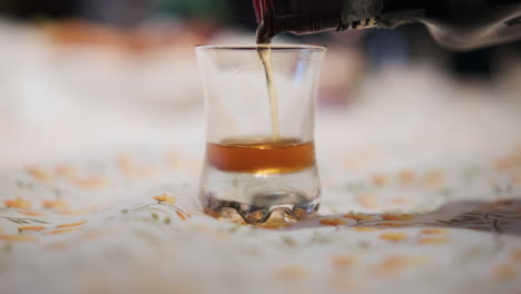 Pouring-Cold-Vecchio-Amaro-del-Capo-Italian-Liqueur-in-Small-Glass-on-Dining-Table,-Close-Up,-Selective-Focus,-Slow-Motion
