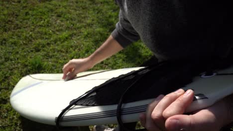 Detail-of-the-hands-of-a-surfer-applying-wax-on-the-surface-of-the-board