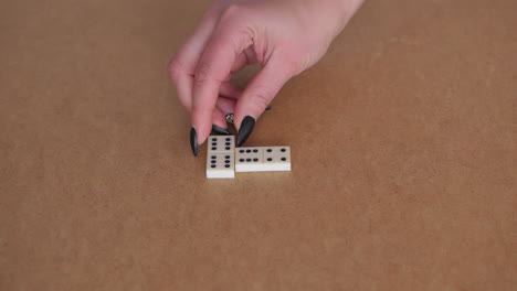 Female-hand-placing-white-domino-next-to-another-one-on-table
