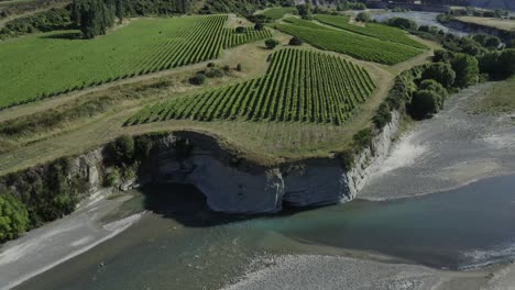 Drone-pulls-back-to-reveal-cliffside-vineyard-next-to-a-river-in-Marlborough-New-Zealand
