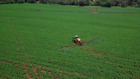 Aerial-view-of-agricultural-tractor-spraying-plantation,-herbicides-and-pesticides