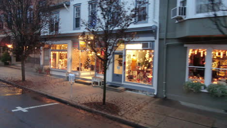 Brightly-illuminated-storefronts-with-Christmas-decoration-in-the-streets-of-a-small-American-town-in-Pennsylvania,-holiday-season-celebration,-shop-sales-in-winter-season