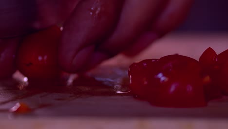 Cutting-red-little-tomatoes-in-half-slice-on-wood-board,close-up-slow-motion