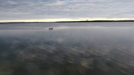 Pontoon-driving-on-a-calm-lake,-4k-Drone-Footage