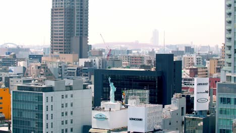 View-of-a-commercial-spot-in-the-city-with-a-statue-of-liberty-replica-on-the-Amerikamura-entertainment-mall-rooftop,-Locked-high-up-shot