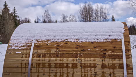 Melting-snow-on-top-of-thermowood-wooden-barrel-sauna,-timelapse