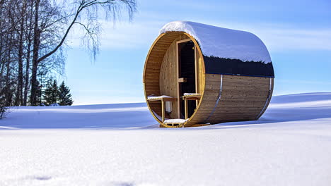 Isolated-thermowood-sauna-barrel-covered-in-snow-during-sunset-time-lapse