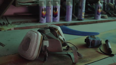 Respirator-mask,-tape-measure,-paint,-other-DIY-workshop-equipment-on-work-bench