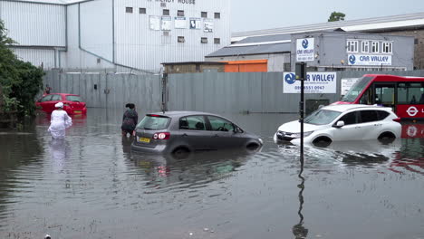 Two-women-wade-through-floodwater-by-submerged-cars-and-a-red-bus-following-thunderstorms-that-saw-more-than-a-month’s-worth-of-torrential-rain-fall-in-several-hours-across-the-capital