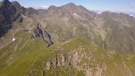 Drohne-Kreist-Hoch-über-Einem-Abgelegenen-Berggipfel-Mit-Wanderern-Und-Rucksacktouristen-Auf-Dem-Gipfel
