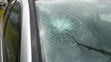 Stolen-car,-vandalized,-and-wrecked-left-abandoned-in-an-empty,-grassy-lot-with-a-broken-windshield