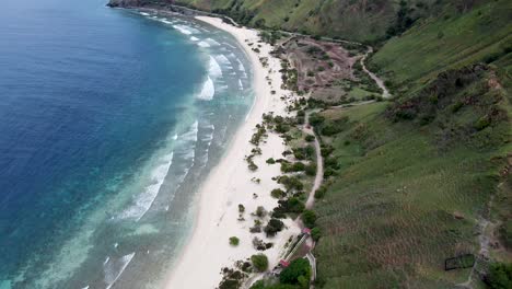 Grüne-Hügel,-Während-Sand,-Blaues-Meer-Und-Rollende-Wellen-Eines-Abgelegenen-Ziels-–-Luftdrohnenaufnahme-Des-Hinteren-Strandes-In-Dili,-Timor-Leste,-Südostasien