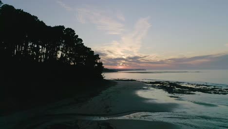 Drone-shot-sunrise-rising-up-over-beach-landscape-with-silhouette-pine-trees-Shoreham