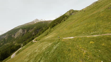 Drone-Siguiendo-A-Un-Ciclista-De-Montaña-Descendiendo-Rápidamente-En-Una-Pista-Cuesta-Abajo-Durante-La-Carrera-Evolenard-2021-En-Val-D&#39;herens,-Valais,-Suiza