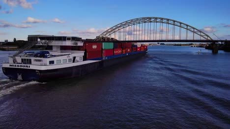 Luftaufnahme-Des-Hecks-Eines-Missouri-Containerschiffs,-Das-Sich-Der-Brücke-Am-Fluss-Noord-Nähert