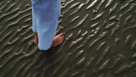 Barefoot-woman-walking-on-wet-sand-of-beach