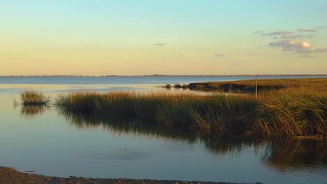 HD-120-fps-pan-left-to-right-from-waterway-view-with-tall-grass-to-reveal-Atlantic-City-skyline-in-distance-with-mostly-clear-sky-near-golden-hour