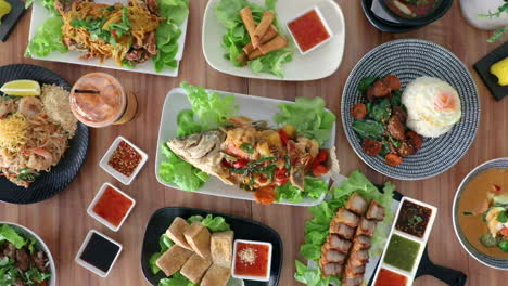 Male-hand-placing-thai-cuisine-spring-roles-onto-flat-lay-food-arrangement