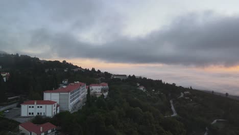 Aerial-forward-over-Golden-Tulip-Caramulo-hotel-and-surrounding-landscape-at-sunrise-on-cloudy-day,-Portugal