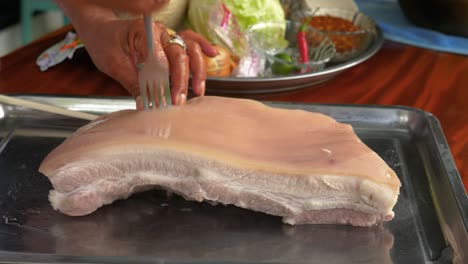 Rubbing-salt-and-stabbing-pork-belly-with-fork-in-handheld-view