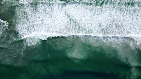 Aerial---Waves-rolling-out,-white-wash-with-sandy-bottom-disturbed,-ascending-drone-shot