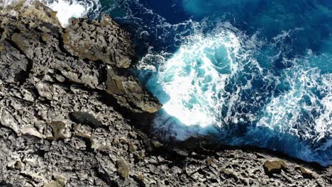 Waves-crashing-in-rocky-coastline-Mellieha-Malta,-Aerial-top-sideways-view
