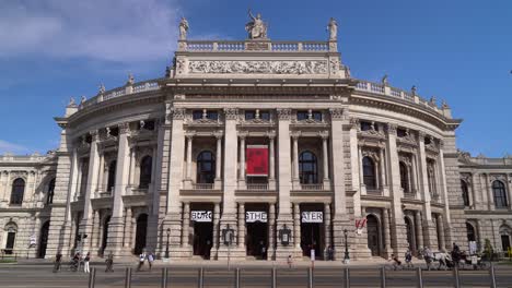Frontal-view-of-typical-Theater-in-Vienna-with-horse-carriage-passing-through