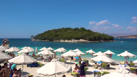 Many-people-gathered-at-beautiful-white-sand-beach-in-Ksamil,-Albania