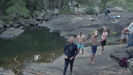 Gruppe-Von-Männern,-Die-Sich-Vor-Dem-Schwimmen-In-Der-Nähe-Des-Wassers-Ausziehen---Rocky-Creek-In-Mount-Byron,-Queensland,-Australien