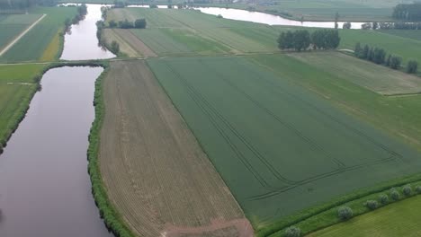 Curvy-river-surrounded-by-rural-agriculture-landscape,-high-angle-drone-view