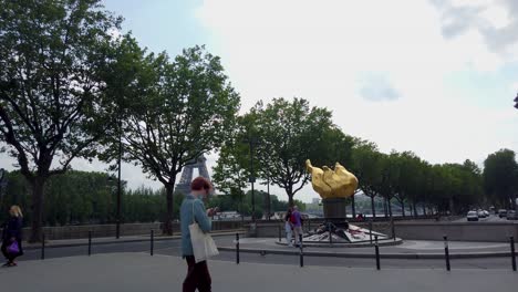 Shot-Of-The-Franco-American-Frienship-Torsh-Of-The-Liberty-Monument-Nearby-The-Pont-de-L'alma-Where-Lady-Diana-Died-With-people-Walking-And-Eiffel-Tower-in-The-Background,-Paris-France