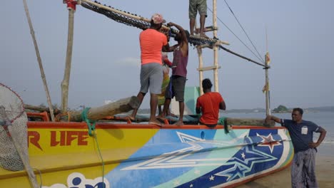 Slomo-static-shot-of-fishermen-preparing-boat-to-go-out-to-sea,-Weligama,-Sri-Lanka