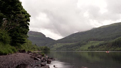 Tranquil-Scottish-Loch-with-Paddleboarder-on-an-Overcast-Day