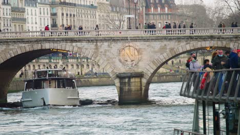 Tourists-riding-on-seine-river-tour-boat-with-tour-guide-and-pedestrians-on-bridge-slow-motion-4k-30p
