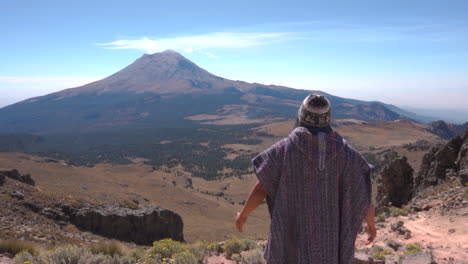 Back-view-of-man-trekker-standing-and-looking-at-steaming-active-Popocatepetl-volcano