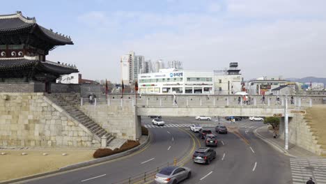 Travellers-exploring-famous-Hwaseong-Fortress-with-cars-traffic-under-the-stony-bridge