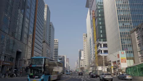 Day-traffic-at-Gangnam-daero-road-with-buses,-cars-and-urban-skyscrapers-in-the-city-centre-in-Gangnam-district